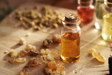 Bottles of aromatherapy essential oils with frankincense resin and dried herbs