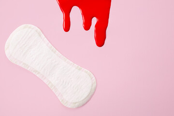 Blood and feminine hygiene pad on pink background. First menstrual period concept