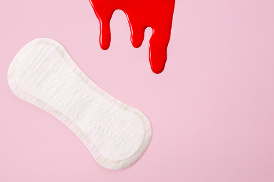 Blood and feminine hygiene pad on pink background. First menstrual period concept