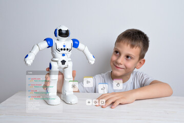 Boy is holding a robot in his hand with conceptual robot programming code