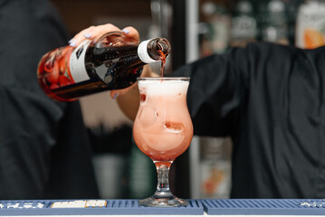 bartender pours alcohol into strawberry cocktail, nightlife concept