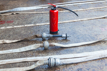 Red fire extinguisher cylinder with unwound fire hoses.