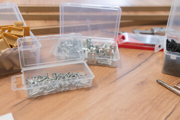 Cluttered workspace with tools and hardware on a wooden surface.