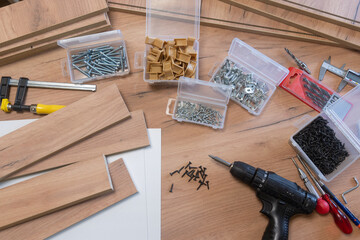 Cluttered workspace with tools and hardware on a wooden surface.