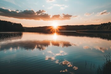 A breathtaking sunset dipping below the horizon, casting a golden radiance over a tranquil lake, complemented by dramatic cloud formations. - obrazy, fototapety, plakaty