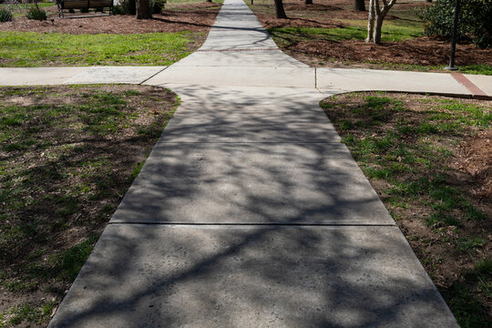 Intersecting sidewalks with one in deep shadows and one in bright light, choices, good and bad, horizontal aspect