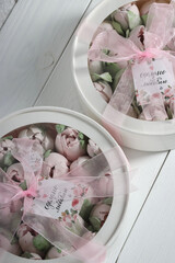 Marshmallows in hatboxes with a transparent lid. The boxes are tied with tape. Tulips made of marshmallows. The inscription in Russian is "Made with love". Homemade marshmallows. View from above.