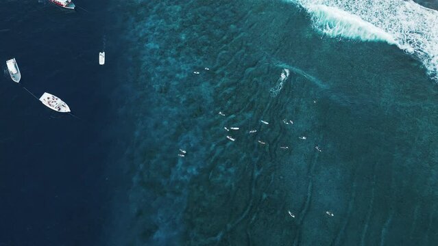 Aerial top down view of the surfing spot in the Maldives with surfers swimming around