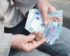 Euro banknotes and coins in the hands of an elderly woman.
