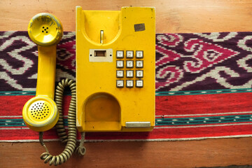 Yellow old fashioned landline telephone that uses the number buttons system to call. Ancient analog...