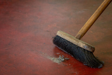 Dust on the floor being swept away with a brush or broom, Image shows a build up a dirt being...