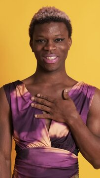 African trans person with colorful dress and make up smiling at the camera