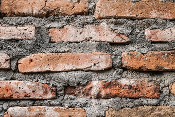 Detail texture of a rough red bricks wall. Unfinished and weathered cement or concrete wall structure. 