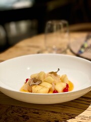 delicacy dish of scallops and truffle in a white plate on a wooden table in a restaurant. High quality photo