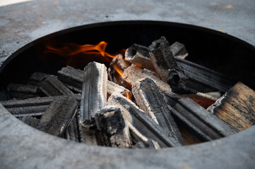 Round barbecue with burning wood and coal. Fire in the grill fire close-up.