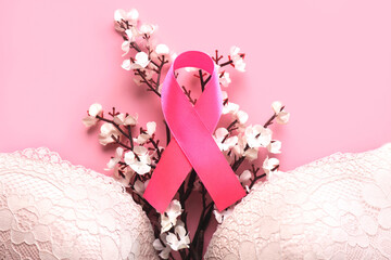 Top view of Women's bra and pink ribbon symbol breast cancer and white almond blossoms. Breast cancer awareness concept