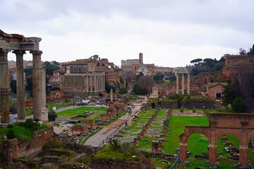 Panoramic view of the Roman forum and ruins of the Basilica Julia public building, on a cloudy day,...