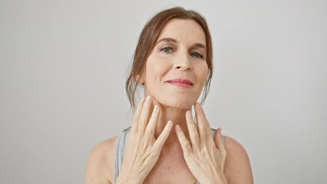 Mature woman touches her face gently against isolated white background, portraying skincare and beauty.