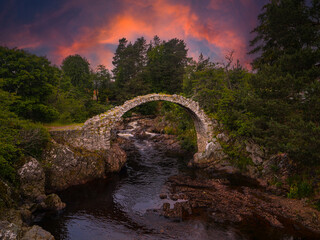 Vibrantly coloured clouds above old stone remains of an arched Coffin Bridge