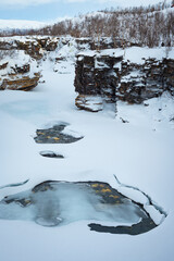 Scenic view of snow, ice, water and steep rock walls of the Abisko River Gorge in Abisko National Park, northern Sweden