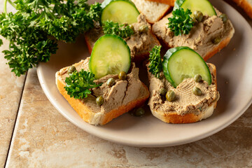 Open sandwiches with pate, cucumber, capers, and parsley.