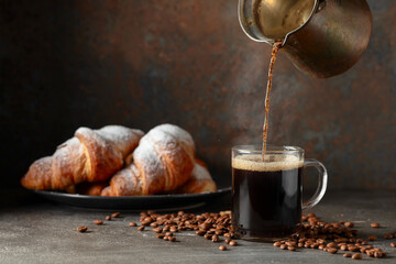 Croissants and black coffee on a kitchen table.