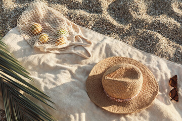 Straw hat, sunglasses, towel, bag on beach sand background. Aesthetic lifestyle, summer vacation concept. Sunbathing, beach party, picnic on summer holiday. Travel fashionable blog, social media.