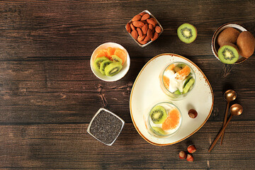 Healthy breakfast with ingredients, background with fruit yogurt, kiwi, muesli, almonds, tangerine...