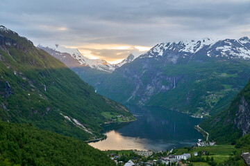 Naklejka na ściany i meble Beautiful Geiranger Fjord is a well known and popular travel destination for cruise ships and offers spectacular views to the norwegian landscape with deep gorges and snow covered mountain ranges.