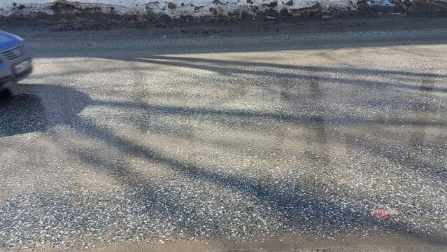 Dirty cars drive along a dirty road in spring, puddles, melted and dirty snow on the sides