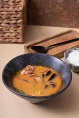 Tom yum soup with seafood and rice on beige background angle view