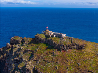 Fototapeta na wymiar Lighthouse at Sao Lourenco peninsula on Madeira from an aerial view. Drone photos of Farol da Ponta de São Lourenço with ocean waves and clouds.