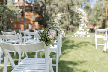 Outdoor wedding ceremony with a stunning floral arch and white chairs set in a serene garden