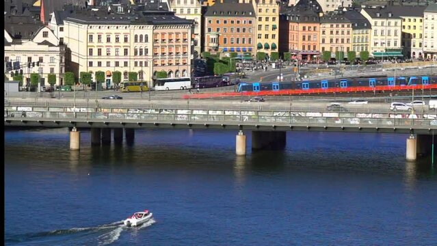 Boats And Trains Near Stockholm'S Colorful Buildings Depict A Vibrant Intersection Of Waterway And Rail Transit Under The Sun