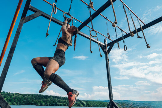 Woman partake in an OCR race while passing the wooden beam with suspensions