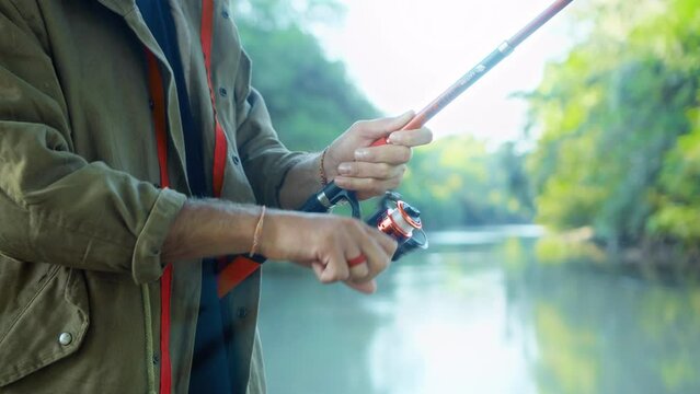 Fishing in nature with a man in a tourist robe. Men's hands hold a fishing rod.