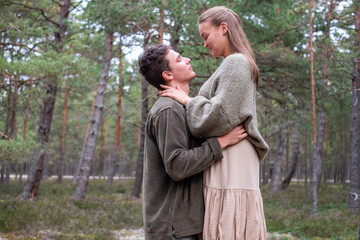 Man and woman in an affectionate embrace in a pine forest. Its a scene of romantic connection in nature, could be used for weeding or engagement themes.