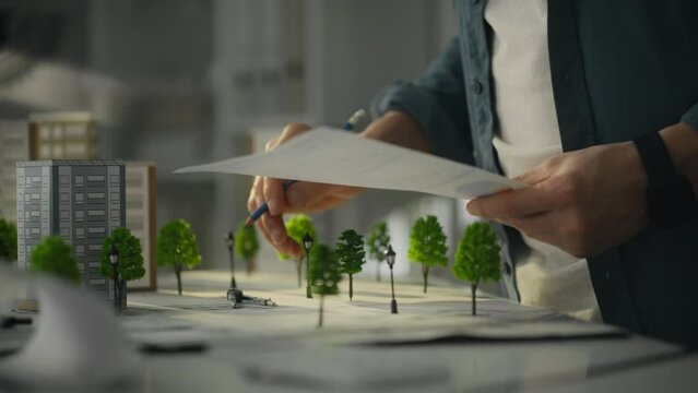 Project plan. A modern design engineer checks the data of a planned building. Architectural designer looking at paper data carriers developing a concept for a sustainable city of the future