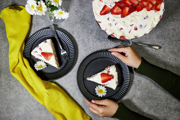 closeup hands holding a strawberry cake or Fraisier in french language in black plate on grunge...