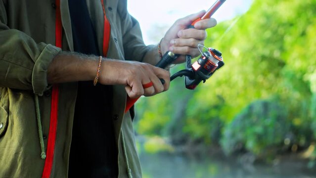 Fishing in nature with a man in a tourist robe. Men's hands hold a fishing rod.