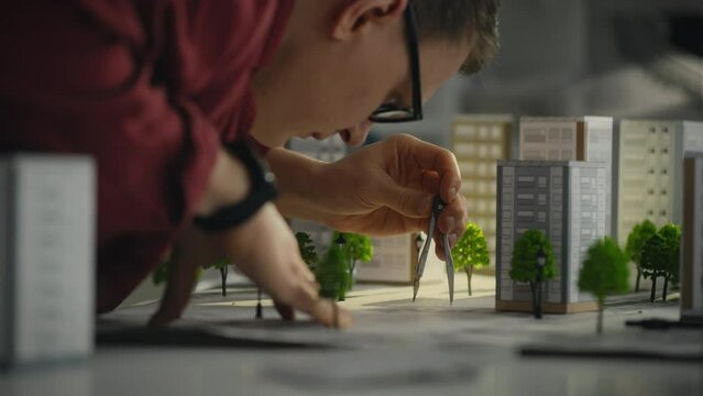 A male worker equipped with a tool works on landscape planning in design office. The designer-constructor is engaged in the design of landscape design and the creation of modern residential apartments