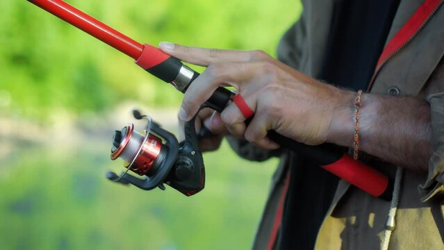 Fishing in nature with a man in a tourist robe. Men's hands hold a fishing rod.