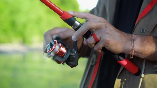 Fishing in nature with a man in a tourist robe. Men's hands hold a fishing rod.