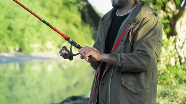 Fishing in nature with a man in a tourist robe. Men's hands hold a fishing rod.