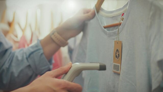 In a clothing store, an Asian worker takes stock of goods by scanning barcodes with a red laser scanner. The manager also uses modern technology to ensure accurate inventory of inventory in the store