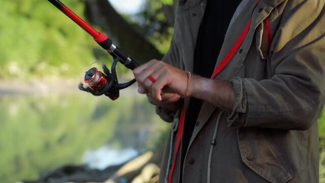 Fishing in nature with a man in a tourist robe. Men's hands hold a fishing rod.