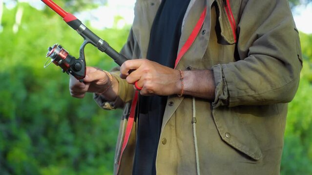 Fishing in nature with a man in a tourist robe. Men's hands hold a fishing rod.
