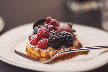 berry tart on table. Delicious pastries. Dessert tarts with raspberries and blueberries on a wooden table. Closeup of fancy gourmet fresh berry dessert tarts.