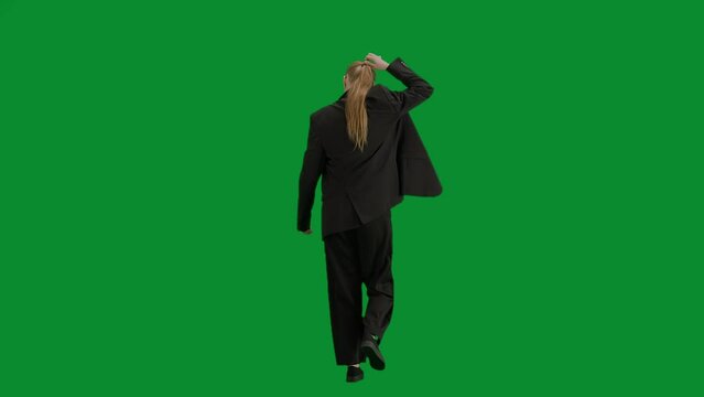 Portrait of female in suit on chroma key green screen. Blonde business woman in formal outfit walking lets her ponytail down and starts dancing. Back view.