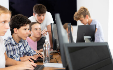 Boy student learning to use computer in group in classroom